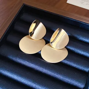 Minimalist gold metal earrings with brushed round texture and high-polish drop detail