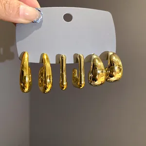 Detailed close-up of three pairs of gold irregular geometric hoop earrings on card