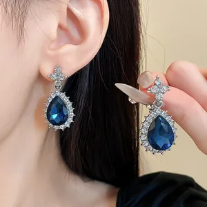 Gros plan sur d'élégantes boucles d'oreilles argentées aux cristaux bleus.