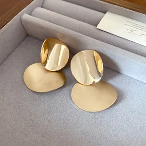 Detailed view of gold metal stud earrings featuring shiny and brushed finishes