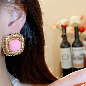 Chic gold-toned twisted square stud earrings with pink center for a trendy fashion look