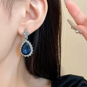 Gros plan de boucles d'oreilles goutte élégantes avec pierre bleue et strass brillants