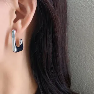 Close-up of minimalist silver irregular geometric U-shaped earring on ear