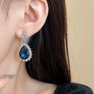 Gros plan d'élégantes boucles d'oreilles en strass bleu foncé en forme de larme