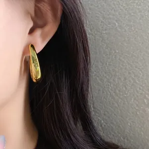 Detailed close-up showing a shiny gold irregular geometric hoop earring worn by a model