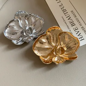 Detailed view of vintage orchid flower brooches in gold and silver textured metal.