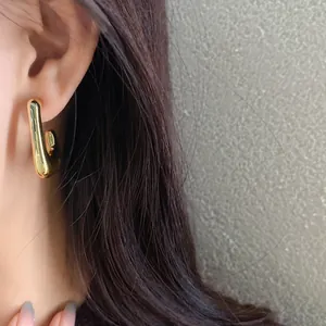 Close-up detail of a minimalist gold irregular geometric stud earring worn on the ear.