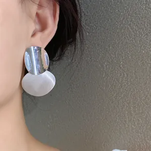 Detailed macro view showing the texture of circular brushed metal earrings on model