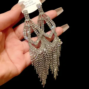 Detailopname van sprankelende lange strass kwastjes oorbellen met zilveren naalden