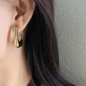 Detailed macro view of an irregular geometric gold-finish minimalist earring worn on an ear