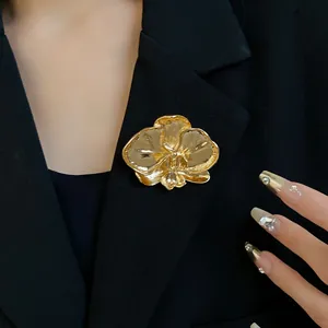 Detailed macro view of a vintage gold orchid flower brooch styled on a professional black blazer