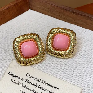 Close-up detail of vintage twisted gold square stud earrings with pink center piece