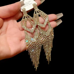 Detailweergave van elegante lange gouden kwastjes oorbellen met glinsterende strass