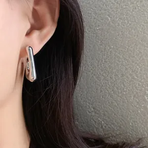 Close-up view of minimalist silver irregular geometric stud earrings on model's ear