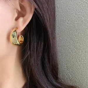 Detail view of a minimalist chunky gold geometric earring worn on a model's ear