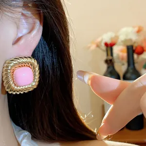 Detailed close-up of a vintage twisted gold-tone square earring with a pink center.