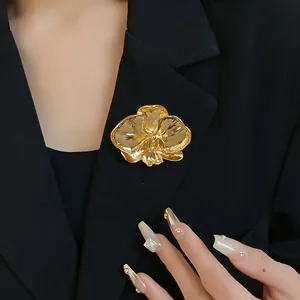 Vintage golden orchid flower brooch pinned on black blazer lapel, detailed view