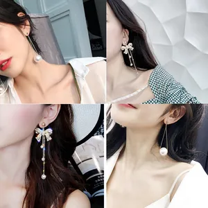 Close-up view of elegant long tassel earrings with dainty pearls worn by a model