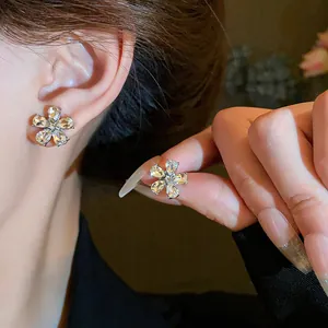 Detailed close-up of elegant silver sparkling crystal flower stud earrings on a model's ear