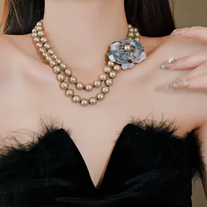 Close-up of double-strand pearl necklace with an ornate blue and white flower pendant