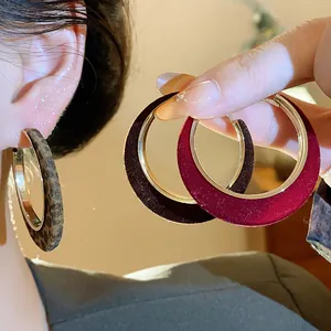 Detailed view showing the velvet flocked texture of large gold hoop earrings in assorted colors