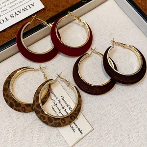 Close-up of flocked hoop earrings in burgundy, brown and leopard print textures.