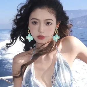 Bohemian style resin flower pendant earrings worn by model with ocean background