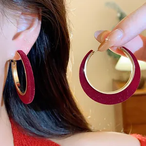Detail view of burgundy red flocked hoop earrings with gold-toned metal finish