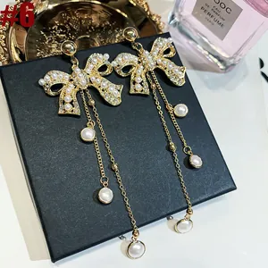 Close-up of elegant French style gold bow earrings with pearl tassels and rhinestones