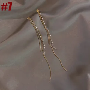 Close-up detail of elegant gold tassel earrings featuring small white pearls on satin fabric