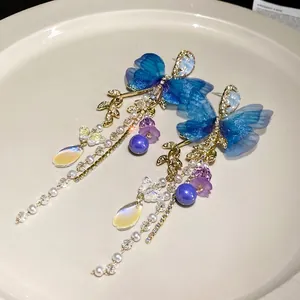 Elegant blue mesh butterfly drop earrings with crystal tassels and pearls on white plate