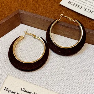 Close-up detail of brown flocked hoop earrings with elegant gold metal lining.