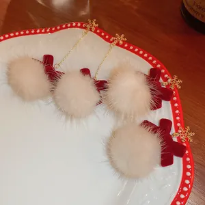 Detailed view of fluffy pom-pom earrings with snowflake and velvet ribbon charms