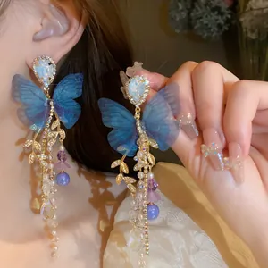 Close-up of elegant blue mesh butterfly earrings with crystal and pearl tassels.