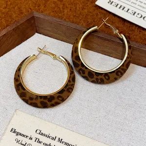 Close-up detail of vintage leopard print flocking hoop earrings with a gold metal finish.