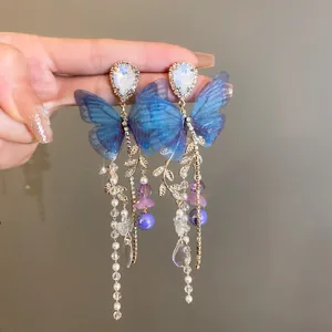 Close-up of elegant blue mesh butterfly earrings with pearl tassels and crystal details