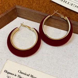 Macro detail of elegant red velvet flocked hoop earrings with gold-toned metal accents