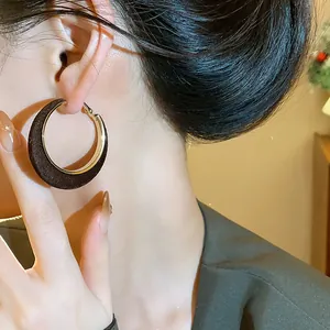 Close-up detail of stylish brown flocked velvet hoop earrings with elegant gold trim