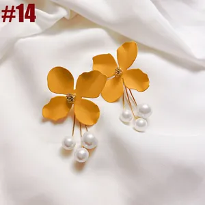 Close-up of yellow flower earrings with pearl tassels on white fabric, French style.