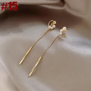 Elegant gold tassel earrings featuring delicate pearls on smooth champagne silk background