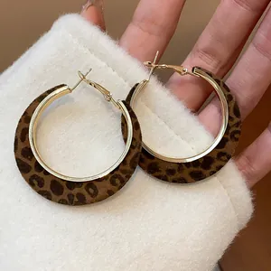 Detailed macro view of stylish gold leopard print flocked hoop earrings with 925 silver needles.