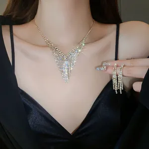 Detail view of a luxury V-shaped rhinestone fringe necklace and long tassel earrings