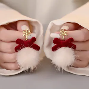 Close-up of Christmas snowflake earrings with red velvet bow and soft white fur ball