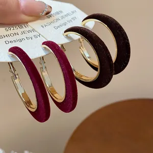 A detailed macro view of wine red and brown velvet flocked hoop earrings on a card