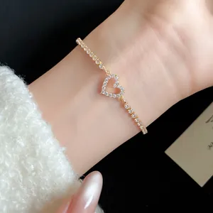 Macro view of gold-tone heart pendant bracelet featuring sparkling zircons on a delicate chain.