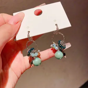 Detailed view of Bohemian earrings featuring light green stones and zircon detailing