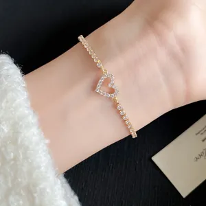Close-up detail of a sparkling gold zircon heart pendant bracelet worn on a wrist.