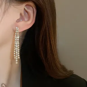 Close-up detail of elegant long rhinestone tassel earrings worn on a model's ear