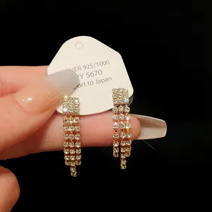 Close-up of elegant gold-toned rhinestone tassel drop earrings with sparkling details.
