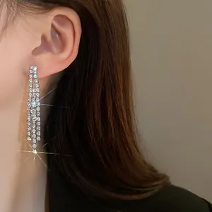 Detailed side view of elegant long sparkling rhinestone fringe tassel earrings worn by a model